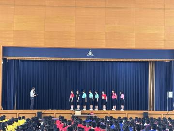 体育館の壇上で学校長からの激励を受ける女子卓球部員の様子