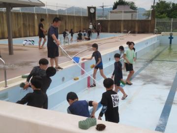 水を流しながらプールをみがく6年生