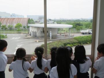 計量器を通るトラックを見学する4年生