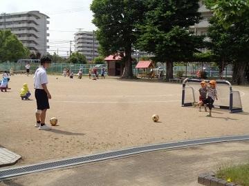 中学生と園児がサッカーをして遊んでいる写真