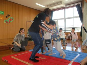 先生と相撲をとる3人の子供