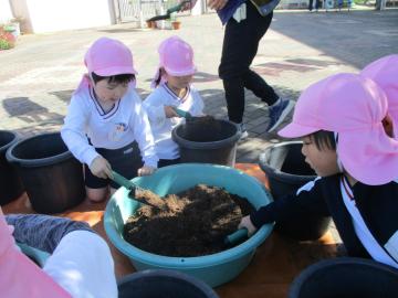スコップを使ってプランターへ土を入れる子供たち