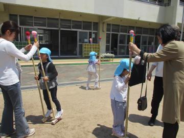 保護者に支えてもらいながら竹馬に乗る子供たち