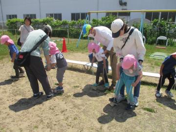 保護者が子供を支えながらぽっくりに乗る様子