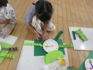 室内でかえるの時計を作る園児の様子