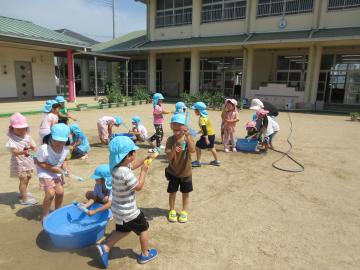 園庭で水鉄砲で遊ぶ園児の様子