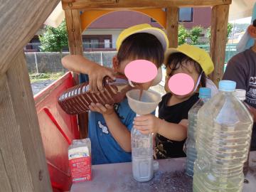 園児が屋外で色水遊びを移し替えている様子