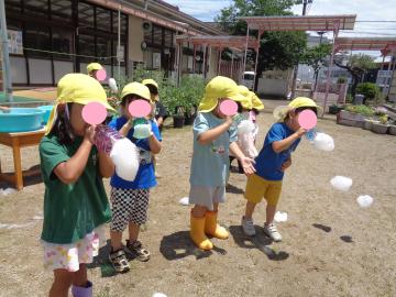 園児が園庭でシャボン玉を吹いている様子