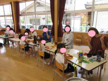 園児が遊戯室内でお家の人と一緒に給食を食べている様子