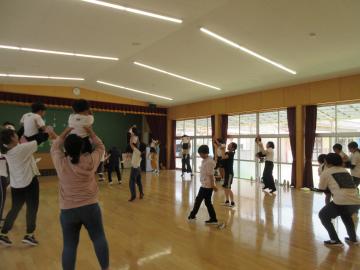 園児が遊戯室内でお家の人にだっこしてもらっている様子