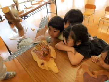 木彫りの野鳥を子ども達が観察している様子