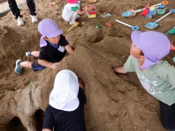 砂場でトンネルを掘る幼児