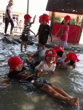 砂場で水遊びをする幼児