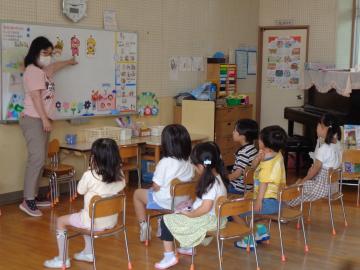 室内で幼児が教師の話を聞いている様子