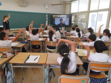 教室内で大きく手をふってオンライン出前講座を終える4年生の様子