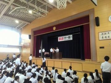 校長先生が表彰状を代表生徒に渡しています