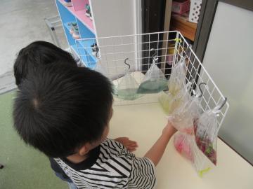 屋外で幼児がつくった色水を見せ合っているところ