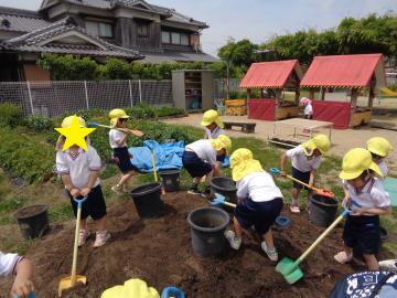 園庭で4歳児がプランターに土を入れている様子