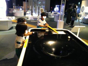 ブラックホールにボールが吸い込まれるところを表現した展示で遊んでいる様子