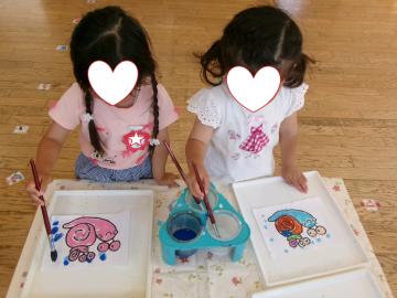 3歳児がカタツムリの塗り絵に絵具で雨を降らしているところ