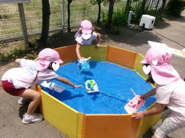 5歳児が園のプールに完成した船を浮かべているところ