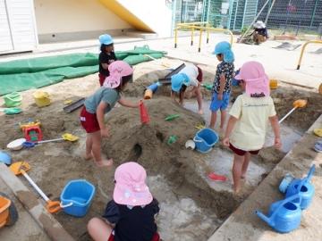 砂場で穴を掘ったり、水を流したりしているところ