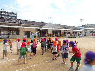 水遊びで園児がホースでシャワーを浴びている様子