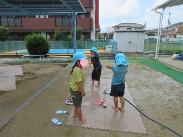 5歳児がスプリンクラーの水で遊んでいるところ