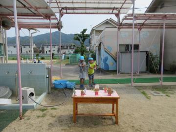 5歳児が手作りの的に向かって水鉄砲をしているところ