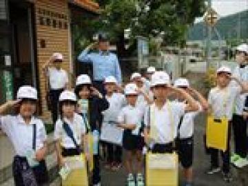 町探検中の児童たちの様子。警察の方と一緒に敬礼しています。