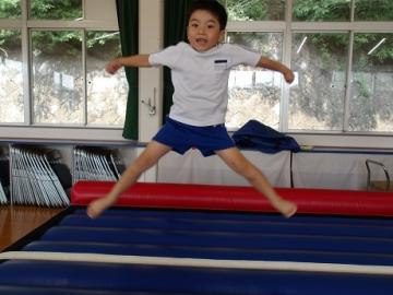 幼児がエアートランポリンで跳びながら開脚する姿