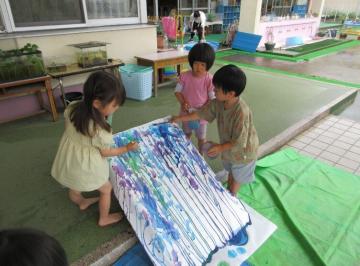 園児たちが模造紙に絵の具を垂らして滑らせている場面2