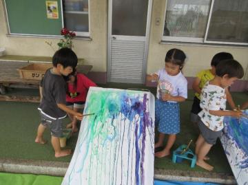 園児たちが模造紙に絵の具を垂らして滑らせている場面1