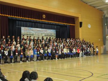 体育館の壇上で6年生が歌を歌っている様子