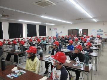 工場見学をする前に注意事項を聞いている児童たちの様子