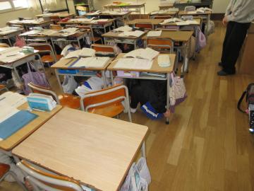 地震が起こって、机の下に避難している様子