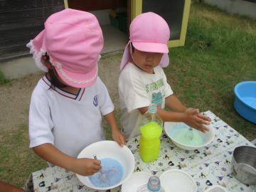 石鹸の泡に色水を混ぜて泡立てる子供