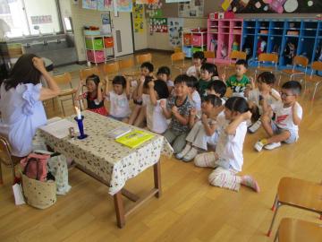 頭にこぶしをのせ先生の真似をする子供