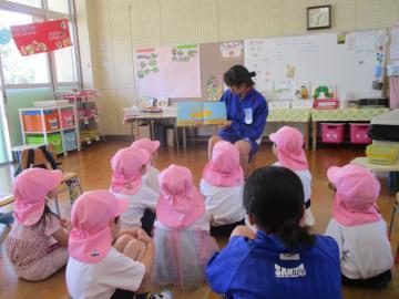 椅子に座って4歳児に絵本の読み聞かせをする中学生