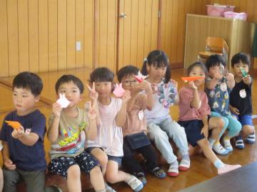 中学生が折った折り紙を嬉しそうに見せる子供たち(1)