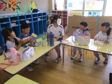一緒に弁当を食べる園児と中学生(1)