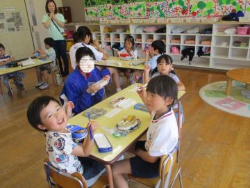一緒に弁当を食べる園児と中学生(2)