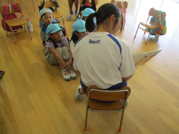 椅子に座って5歳児に絵本の読み聞かせをする中学生