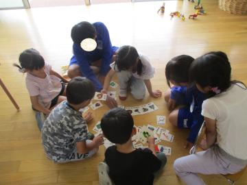 しりとりのカードを並べて遊ぶ園児と中学生