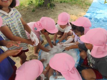 屋外で4歳児たちがタライに泡を作っている様子