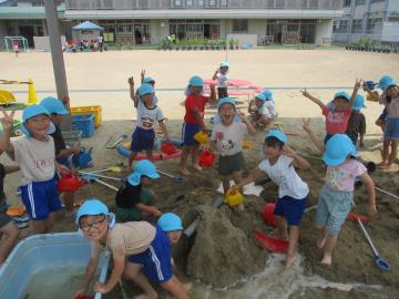 砂場で水遊びを楽しむ園児たちの様子