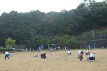 運動場の草引きをしている様子