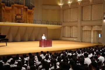パルナソスホール舞台上で生徒指導部長が訓話をする様子