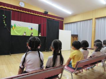 遊戯室でたぬきの人形劇を見ている園児たちの様子