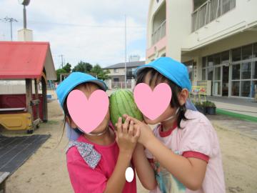 園庭で園児がスイカを持っている様子